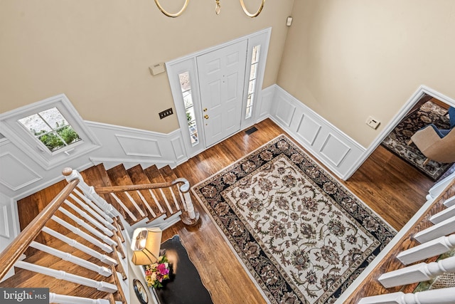 foyer featuring stairway, plenty of natural light, wood finished floors, and wainscoting