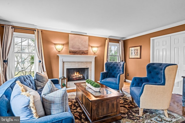 living area with a fireplace, crown molding, baseboards, and wood finished floors