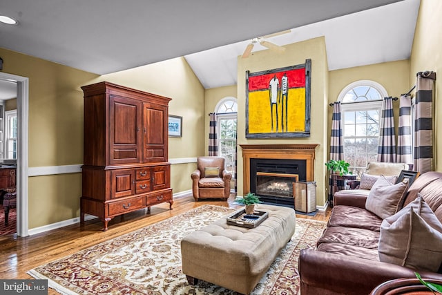 living area featuring plenty of natural light, baseboards, a fireplace with flush hearth, and wood finished floors