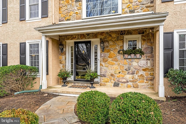 property entrance featuring stucco siding and stone siding