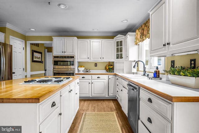 kitchen featuring a sink, appliances with stainless steel finishes, white cabinets, and butcher block counters