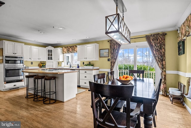 dining room with crown molding, light wood-style flooring, and baseboards