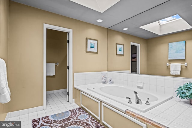 bathroom featuring baseboards, a skylight, recessed lighting, tile patterned flooring, and a bath