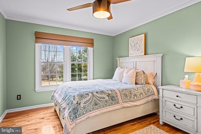 bedroom featuring baseboards, wood finished floors, and crown molding