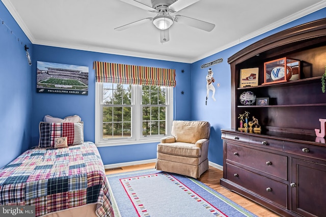 bedroom with light wood finished floors, visible vents, baseboards, ornamental molding, and a ceiling fan