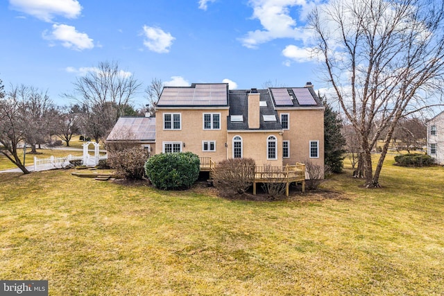 back of house featuring fence, solar panels, a yard, a chimney, and a deck