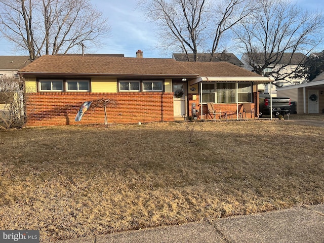 ranch-style house featuring a front yard, brick siding, and a sunroom