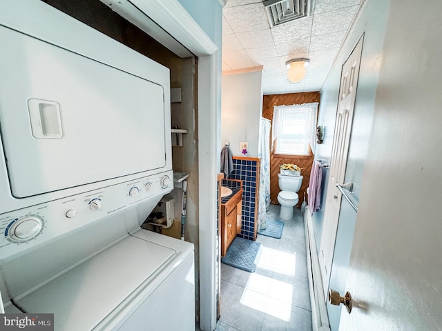 laundry room with visible vents, stacked washer and dryer, laundry area, and tile patterned flooring