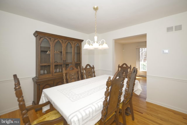 dining area featuring baseboards, an inviting chandelier, visible vents, and light wood-style floors