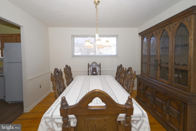 dining area featuring light wood-style flooring and an inviting chandelier