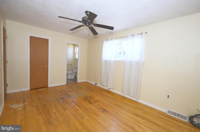 unfurnished bedroom featuring baseboards, visible vents, hardwood / wood-style flooring, ceiling fan, and ensuite bathroom