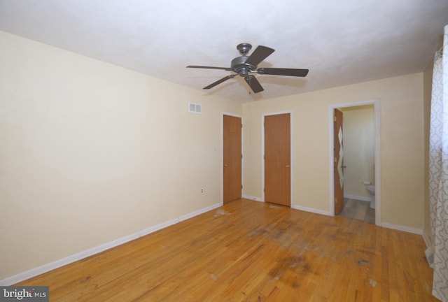 unfurnished bedroom featuring ceiling fan, visible vents, baseboards, light wood-type flooring, and ensuite bath