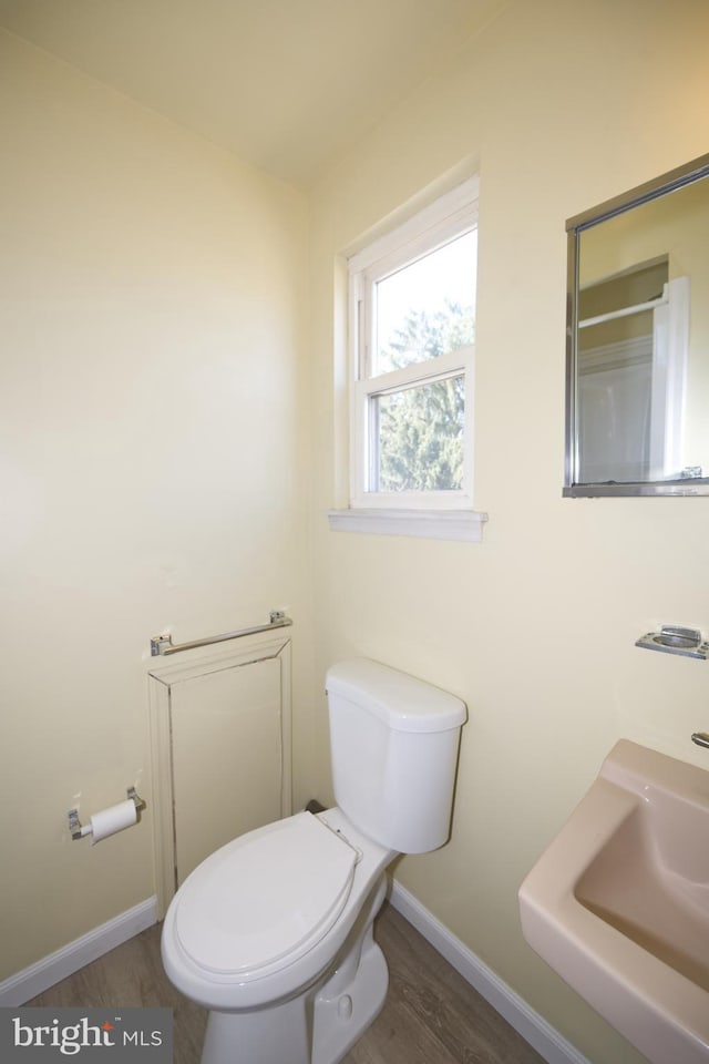 bathroom featuring baseboards, a sink, toilet, and wood finished floors