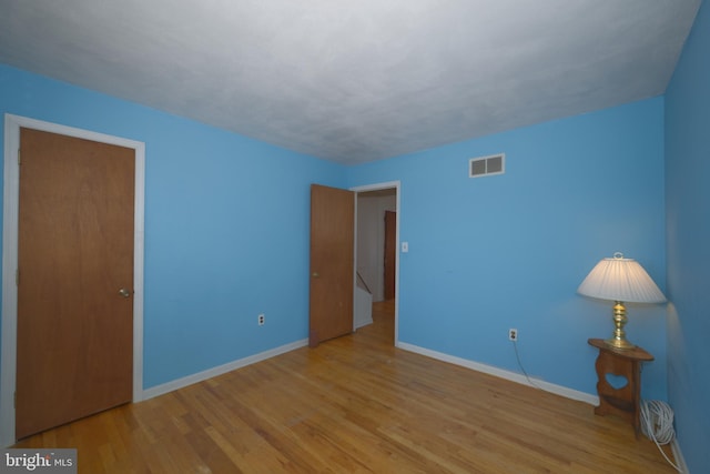 unfurnished bedroom with visible vents, baseboards, and wood finished floors