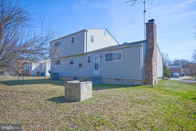 back of property with entry steps, a lawn, a chimney, and cooling unit