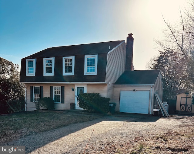 view of front of home featuring an outbuilding, driveway, a shed, an attached garage, and a chimney