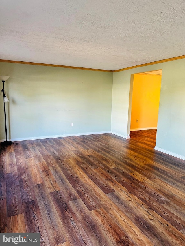 spare room featuring crown molding, baseboards, wood-type flooring, and a textured ceiling