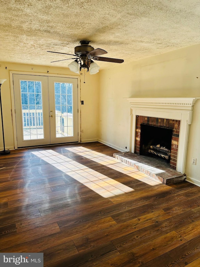 unfurnished living room featuring a brick fireplace, a textured ceiling, baseboards, and hardwood / wood-style floors