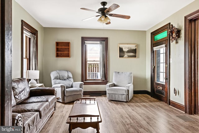 sitting room with visible vents, light wood-style flooring, baseboards, and ceiling fan