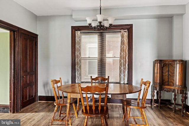 dining space featuring an inviting chandelier, wood finished floors, and baseboards