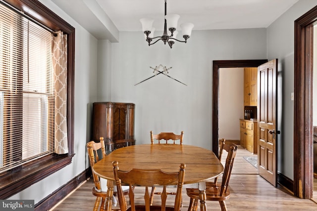 dining area featuring light wood-type flooring, baseboards, and an inviting chandelier