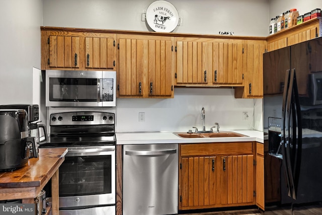 kitchen featuring a sink, stainless steel appliances, brown cabinetry, and light countertops