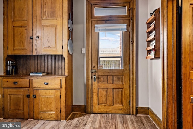 doorway with light wood-type flooring and baseboards