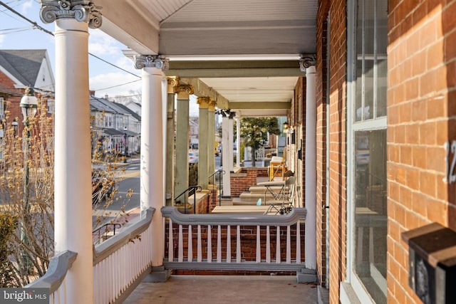 exterior space featuring covered porch and brick siding