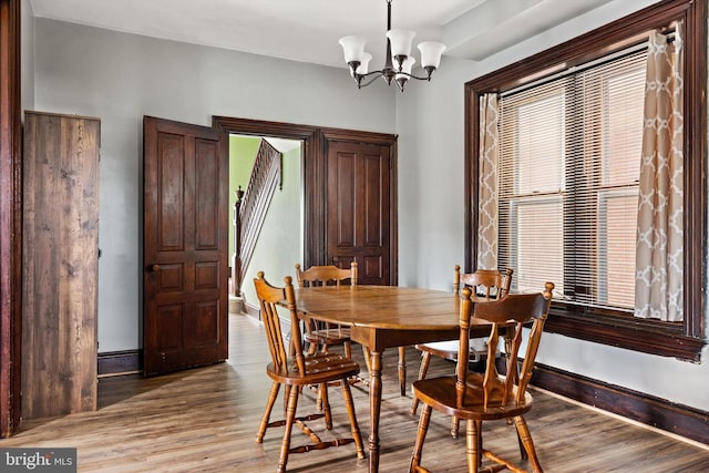 dining area with baseboards, light wood-style floors, and an inviting chandelier