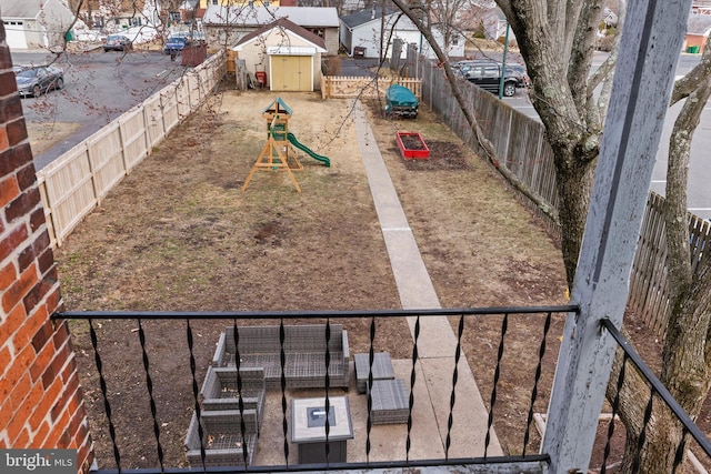 view of yard featuring a playground, a fenced backyard, and a residential view