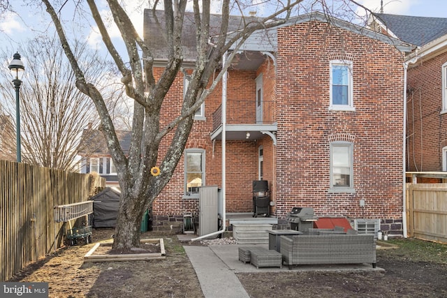 back of house featuring brick siding, roof with shingles, and a fenced backyard