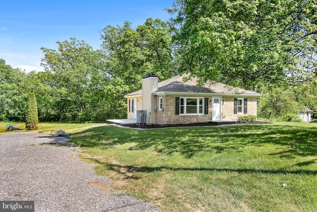 view of front facade with a front yard, stone siding, central AC, and a chimney