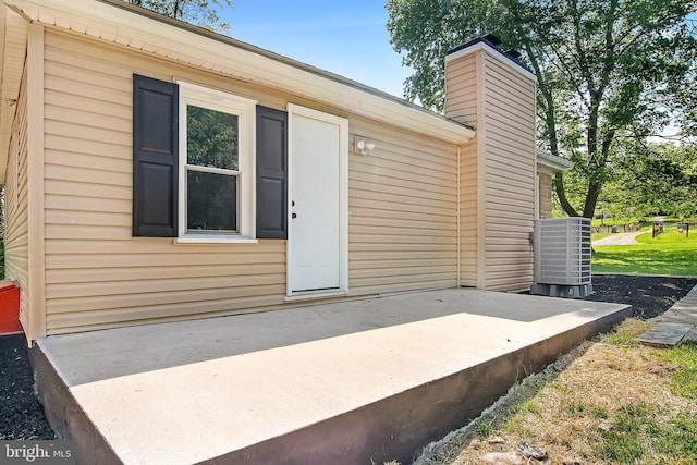 entrance to property with a chimney and central air condition unit