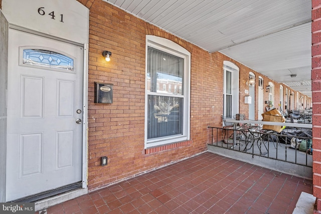 entrance to property with covered porch and brick siding