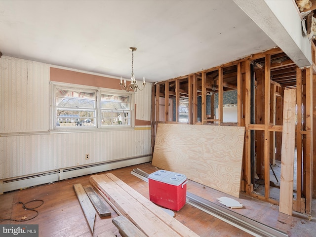 unfurnished dining area with a notable chandelier, a baseboard heating unit, and wood-type flooring