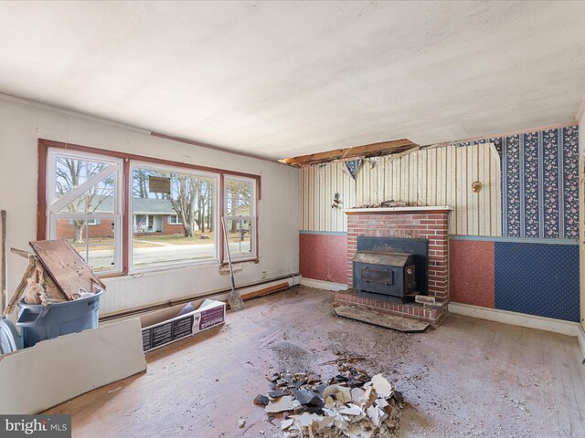 unfurnished living room with wallpapered walls, a wood stove, and baseboards