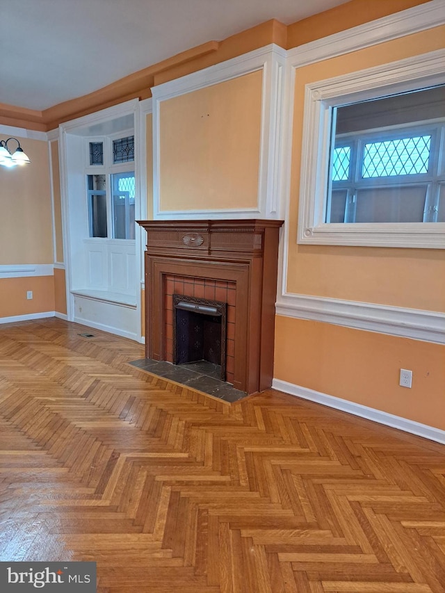 unfurnished living room with a tile fireplace and baseboards