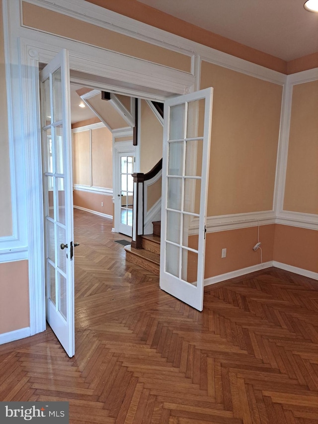 spare room featuring baseboards, stairway, and french doors