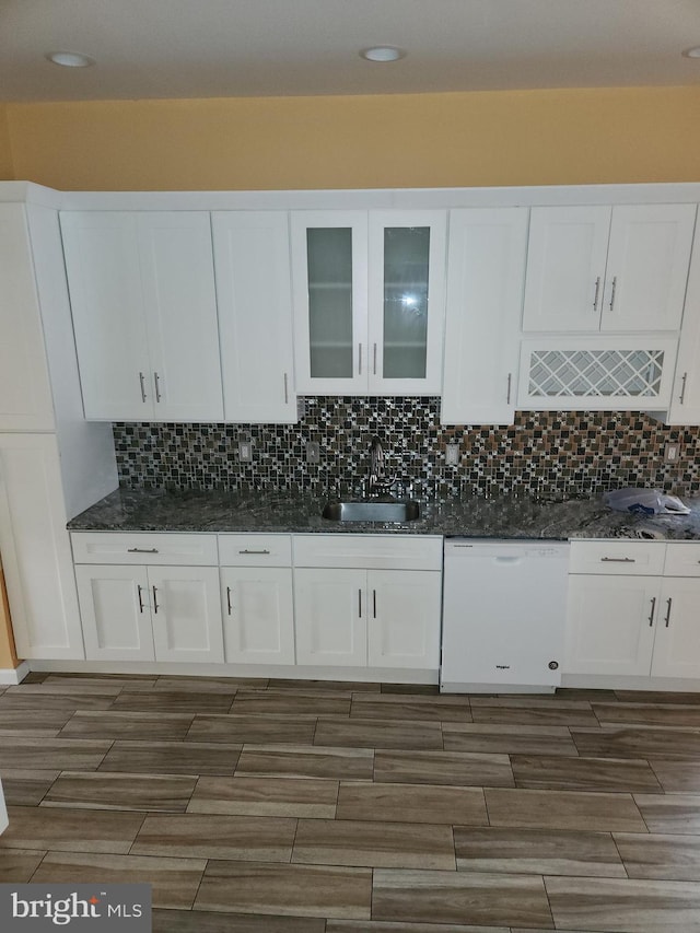 kitchen with tasteful backsplash, white dishwasher, white cabinets, and a sink