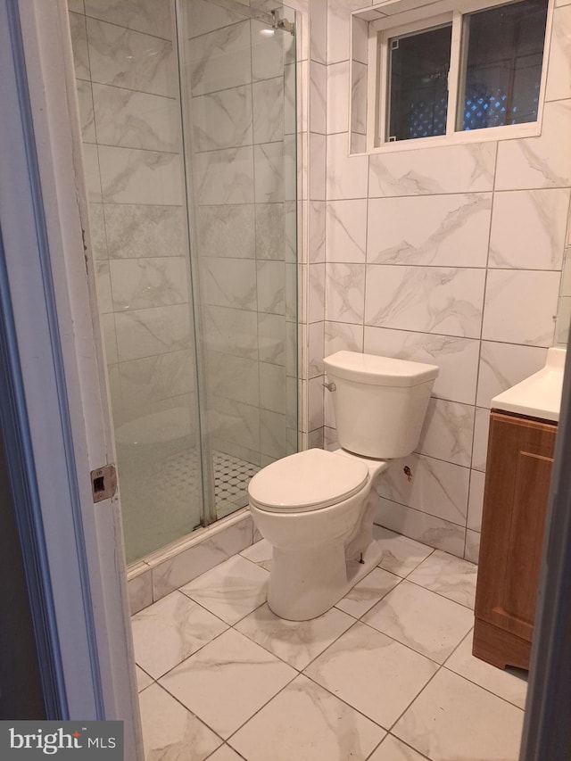 bathroom featuring marble finish floor, a shower stall, toilet, and vanity