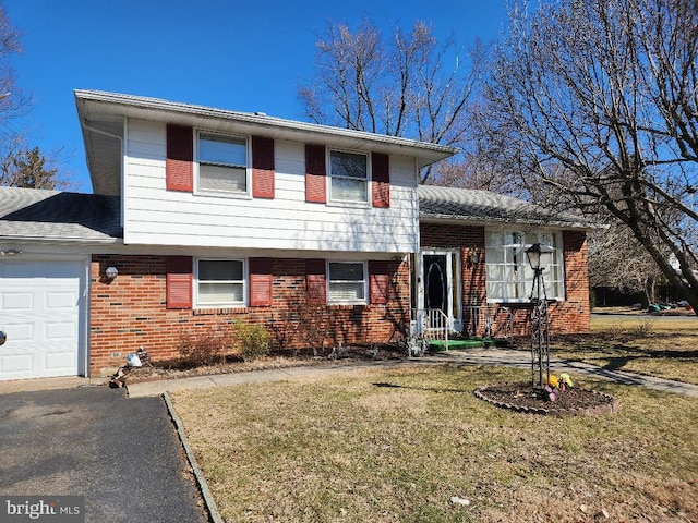 split level home featuring a front yard, brick siding, and an attached garage