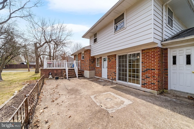 back of property with brick siding, a patio area, a deck, and fence