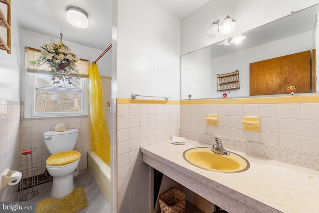 bathroom with tile walls, toilet, and a wainscoted wall