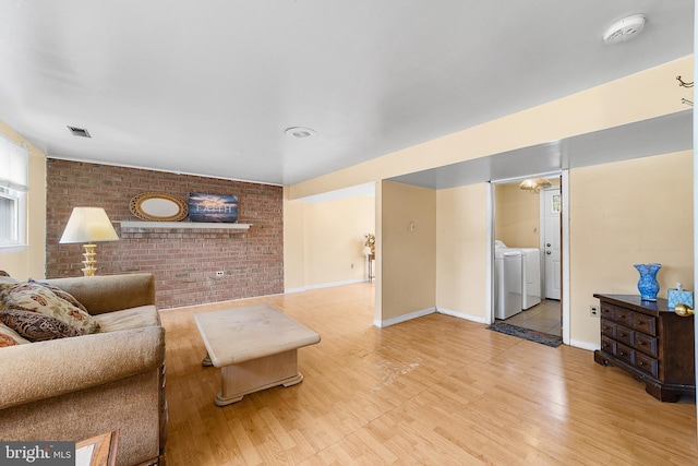 living room featuring visible vents, washing machine and dryer, brick wall, and wood finished floors