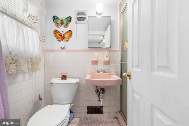 bathroom featuring a wainscoted wall, visible vents, a sink, tile walls, and toilet