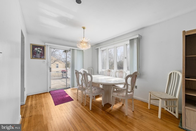 dining area with a chandelier, baseboards, and light wood-style flooring