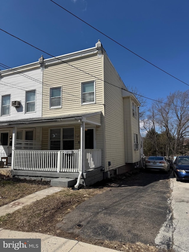 townhome / multi-family property featuring a porch, an AC wall unit, and driveway