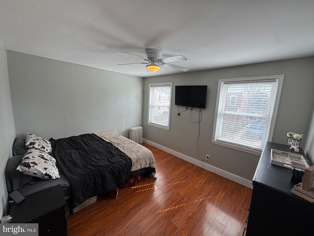 bedroom featuring ceiling fan, baseboards, radiator, and wood finished floors