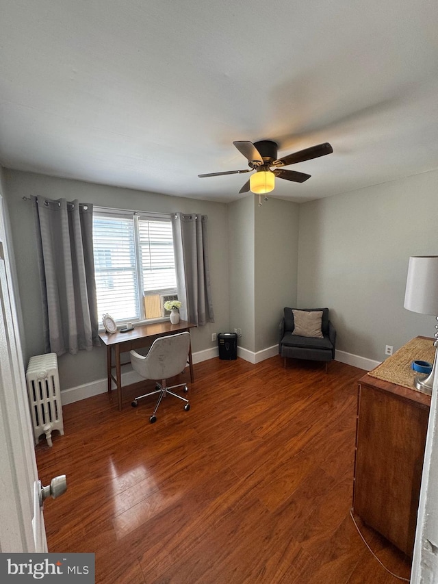 office space featuring radiator, a ceiling fan, baseboards, and wood finished floors