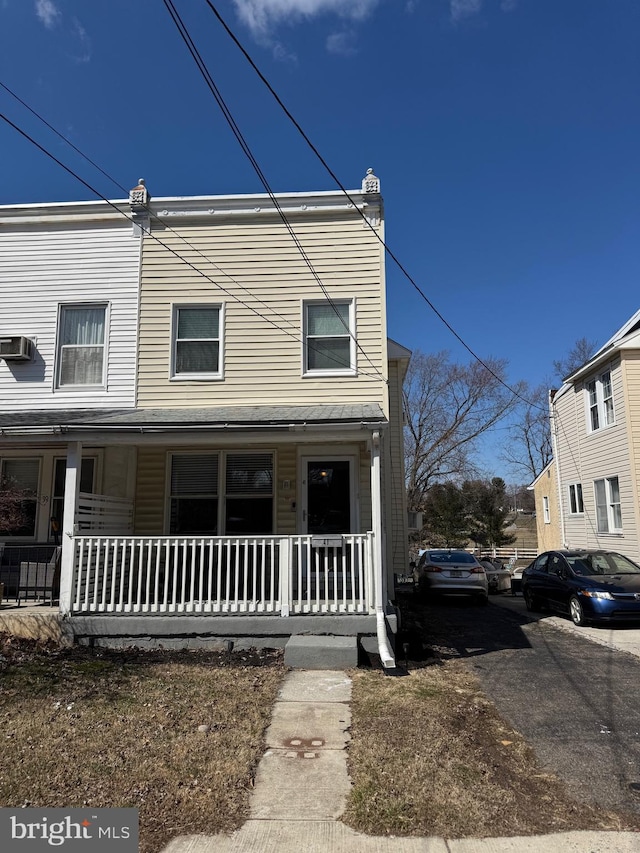 multi unit property featuring a chimney, covered porch, and an AC wall unit